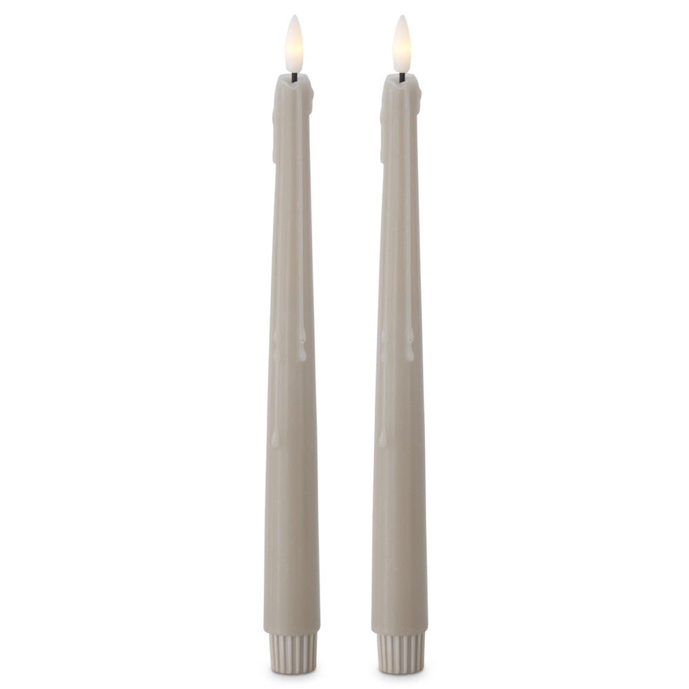 Two lit, taupe flameless taper candles with faux dripping wax effects against a white background.