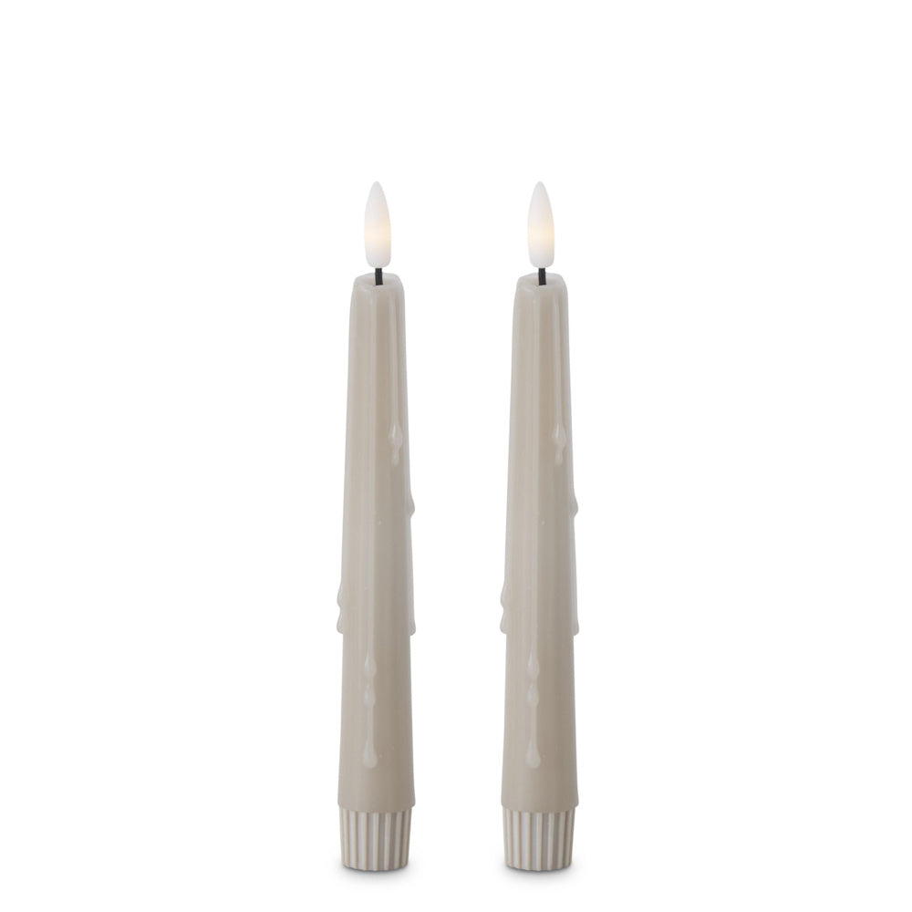Two taupe, dripping taper flameless LED candles standing side by side against a white background.