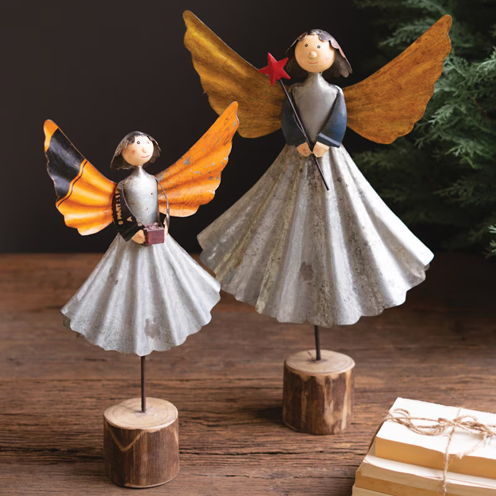 Set of two recycled metal angel figurines with rustic wooden bases on a wooden table.