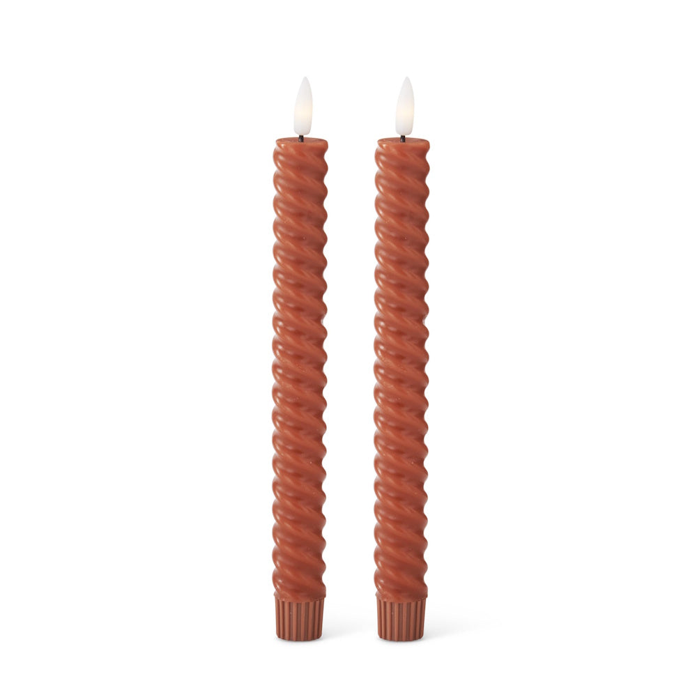 Two rust spiral taper candles with glowing faux flames against a plain white background.