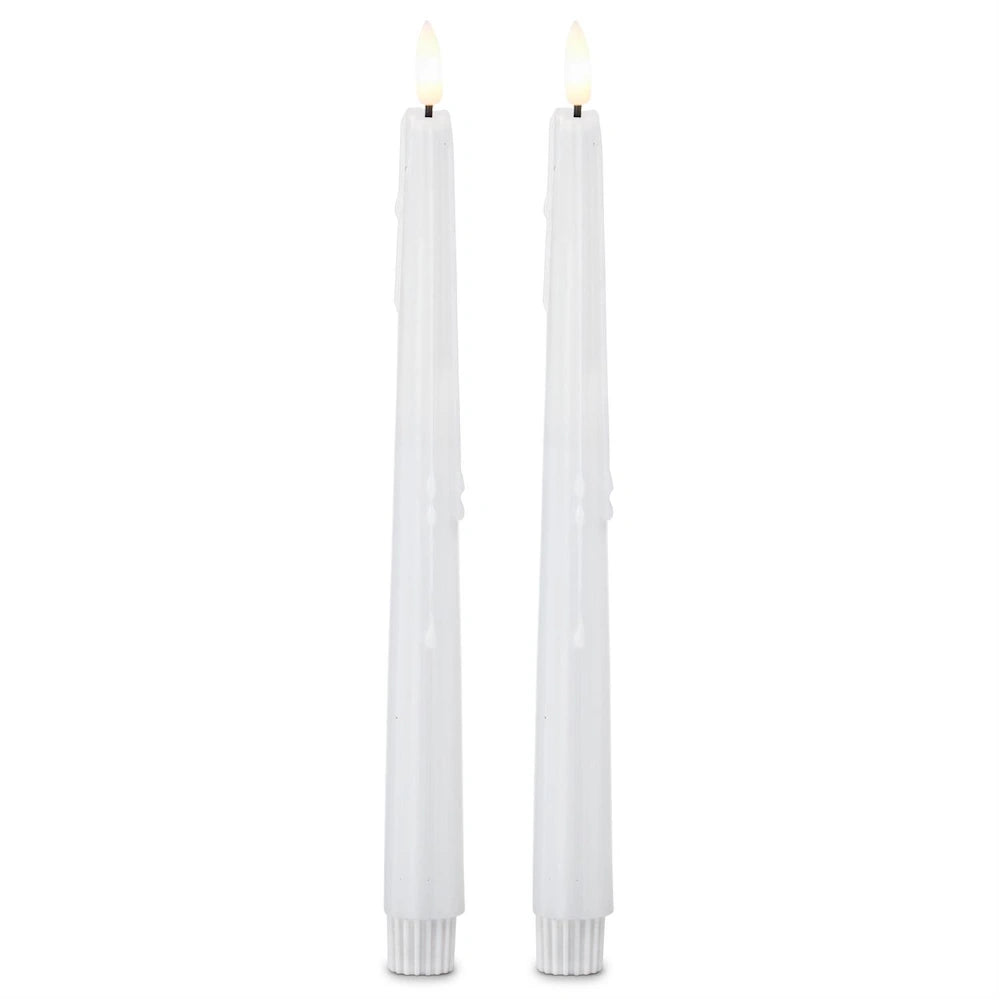 Two tall, white flameless taper candles with faux dripping wax and lit LED flames against a white background.