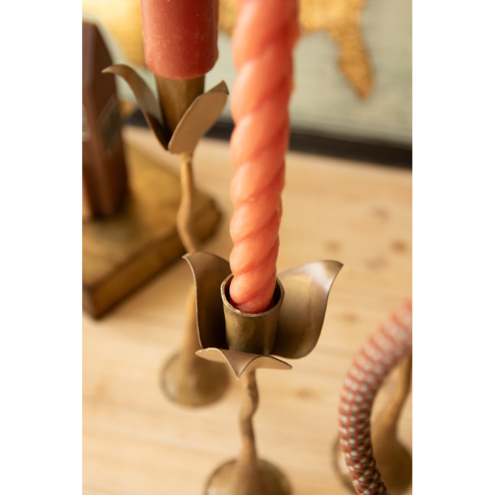 Top-down close-up of a leaf-shaped cup holding a spiral pink candle on a brass taper holder.