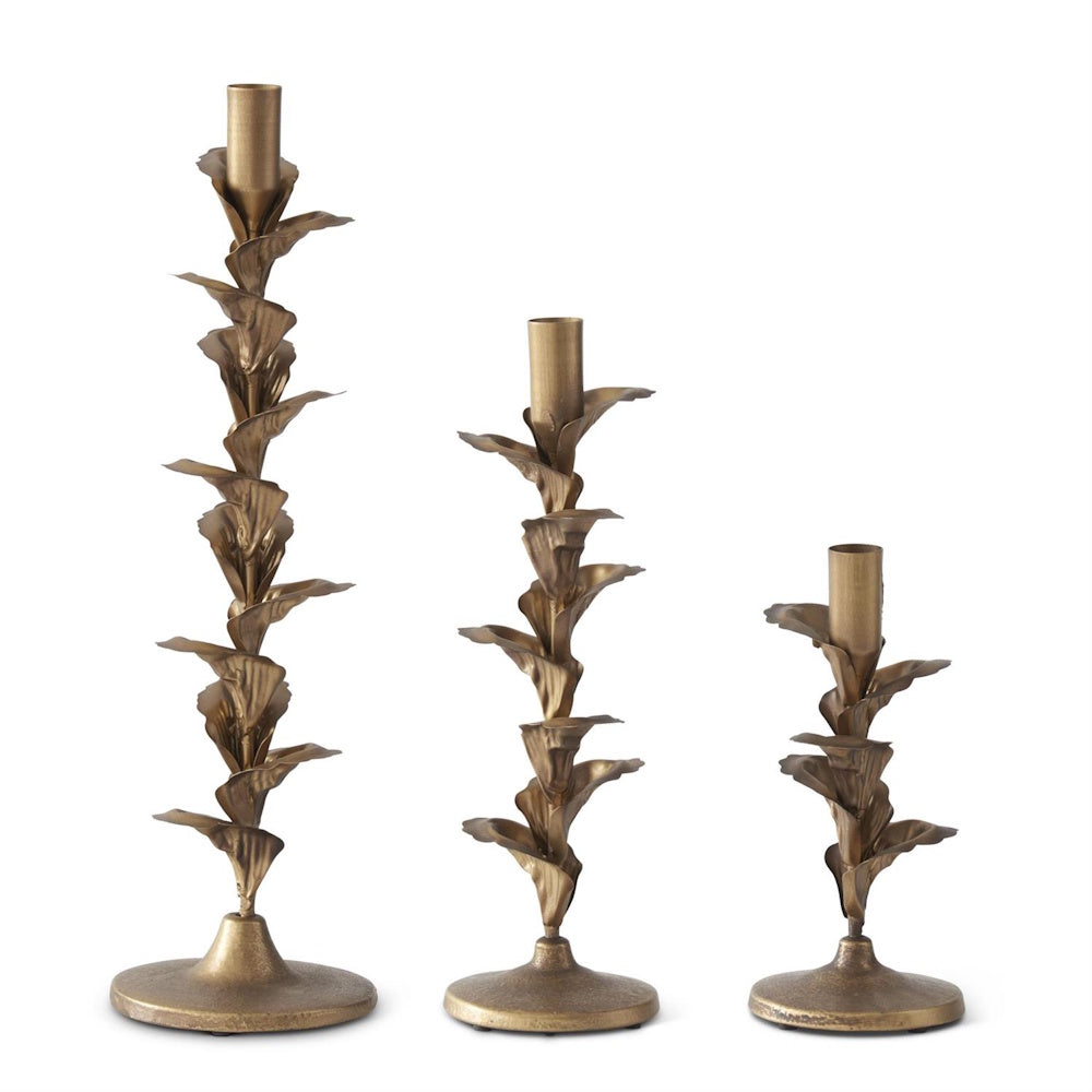Set of 3 gold metal floral petal taper candle holders in varied heights on a white background.