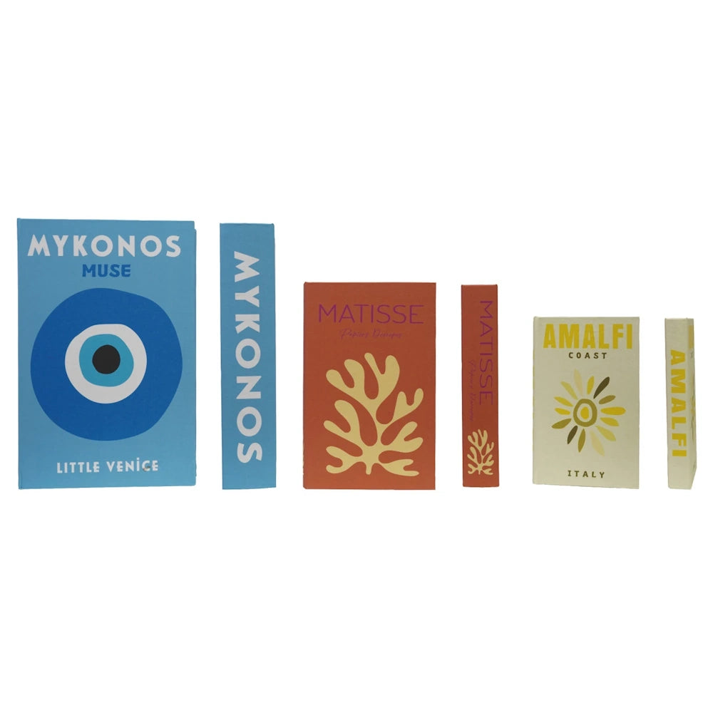 Assorted decorative travel and art books including Mykonos Muse, Matisse, and Amalfi Coast on a white background.