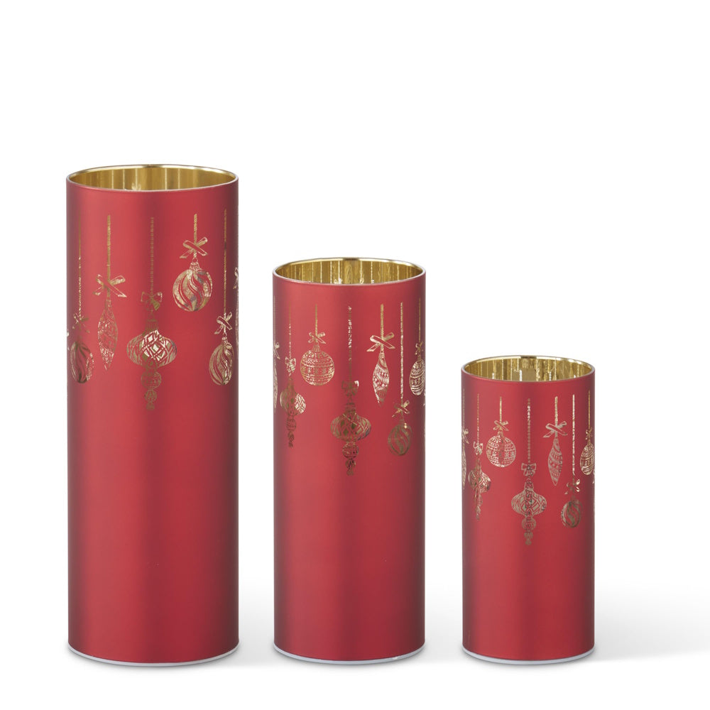A set of three red laser-engraved cylinders featuring hanging ornament patterns and gold interiors.