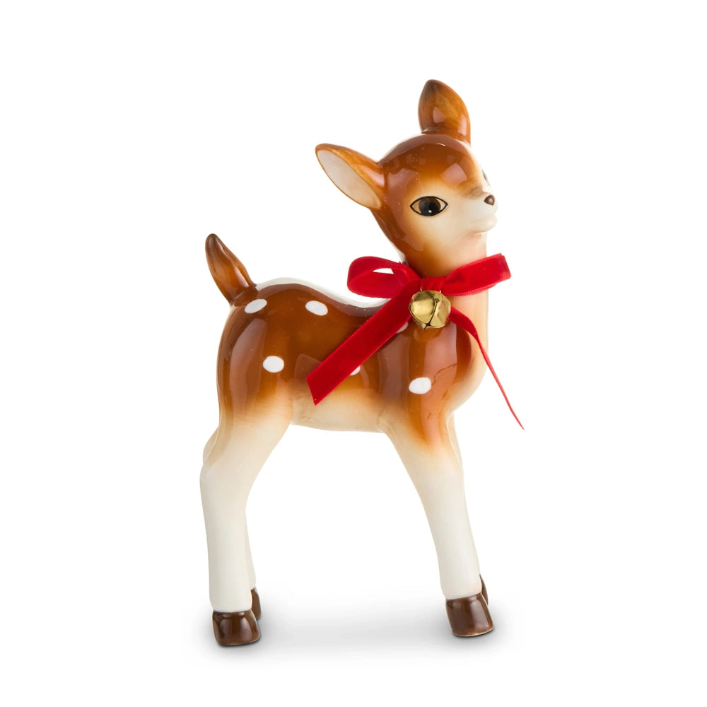 Side profile of a ceramic deer figurine with white spots, wearing a red ribbon and gold bell.
