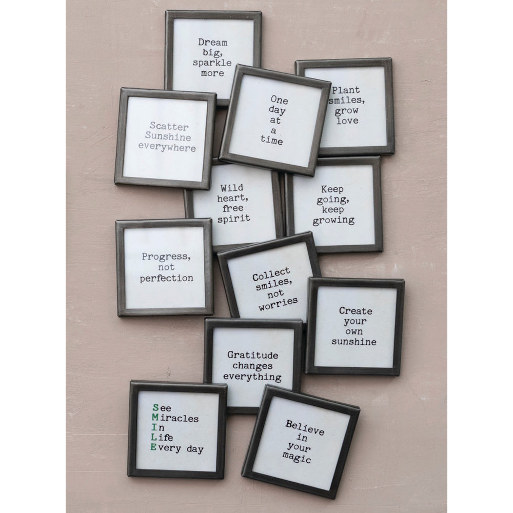 An arrangement of twelve square silver-framed motivational signs displayed together on a wall.