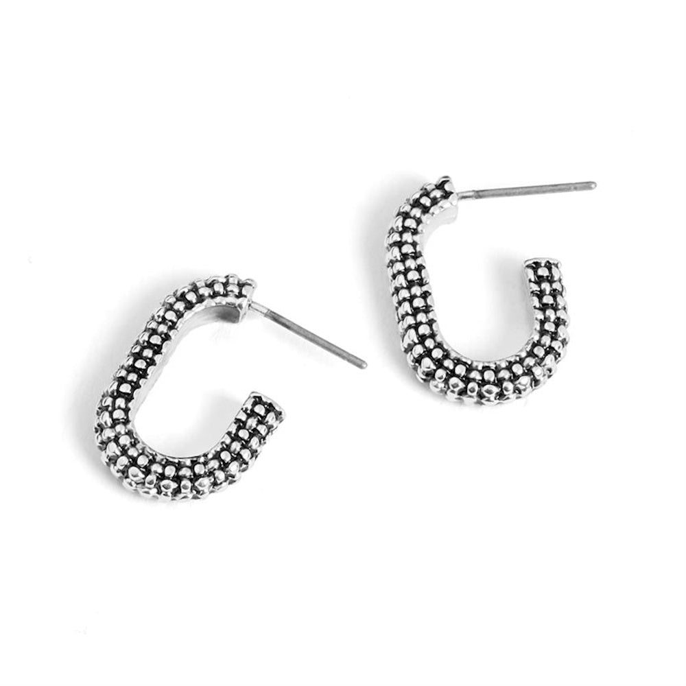 Textured silver oval hoop earrings with a beaded, studded design and post back closure on a white background.