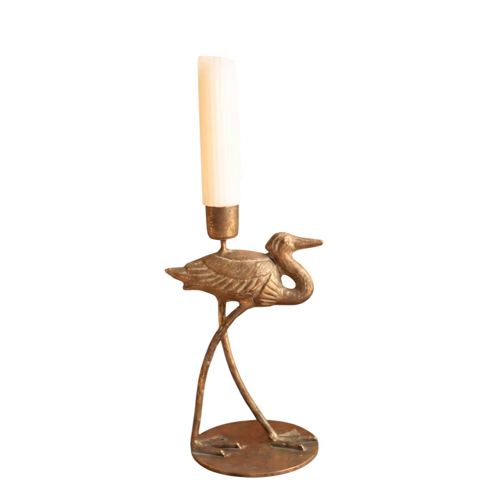 Small antique brass shorebird taper candleholder holding a white candle on a white background.