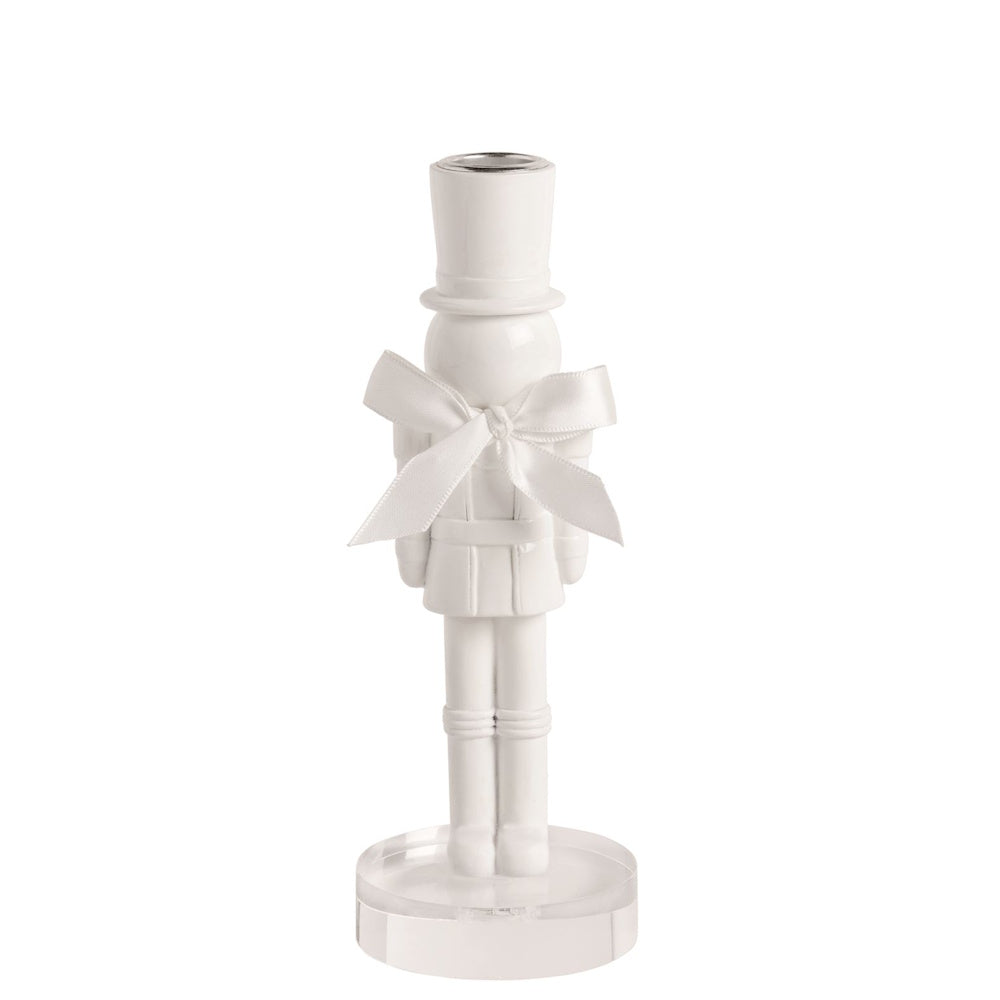 Small white lacquered nutcracker candlestick holder with a satin bow on a clear acrylic base.
