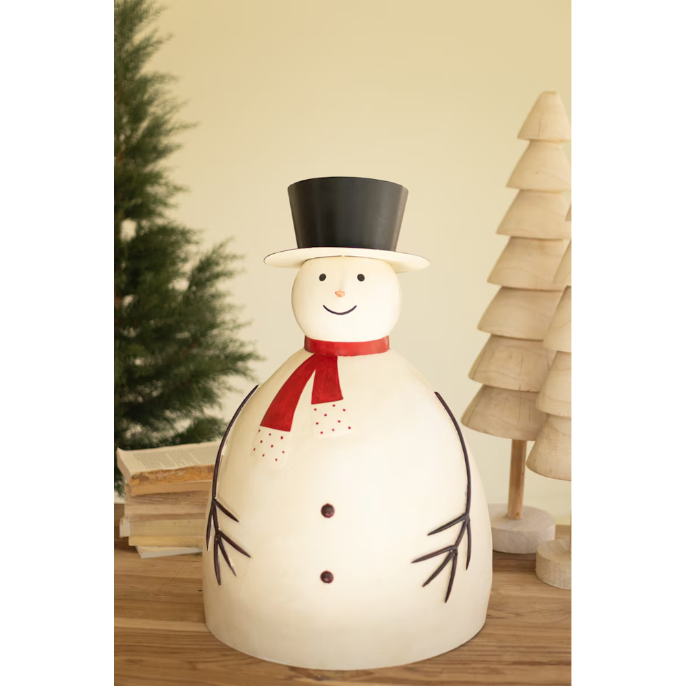 Painted metal snowman sculpture styled on a wooden surface with Christmas decor accents.