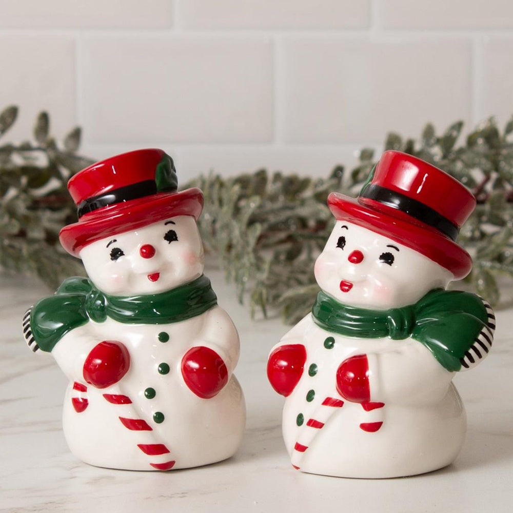 Ceramic snowman salt and pepper shakers wearing red top hats, green scarves, and holding candy canes.