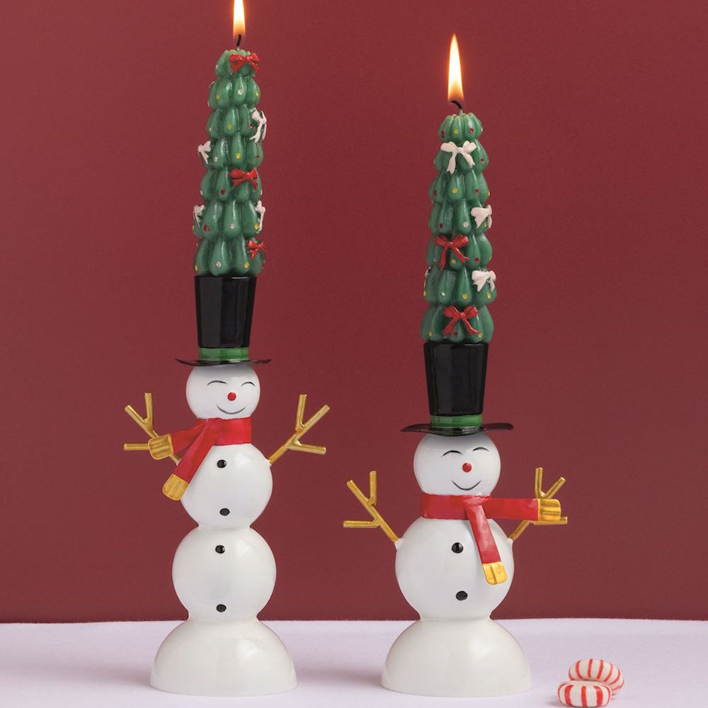 Two snowman taper candle holders displayed with lit Christmas tree taper candles on a holiday table.