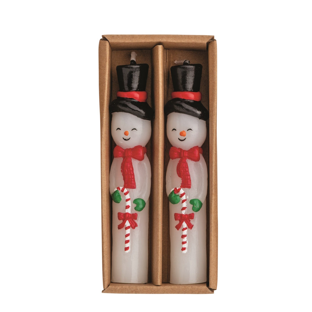 Flat lay view of two white wax snowman mini taper candles with black top hats in a brown cardboard box.
