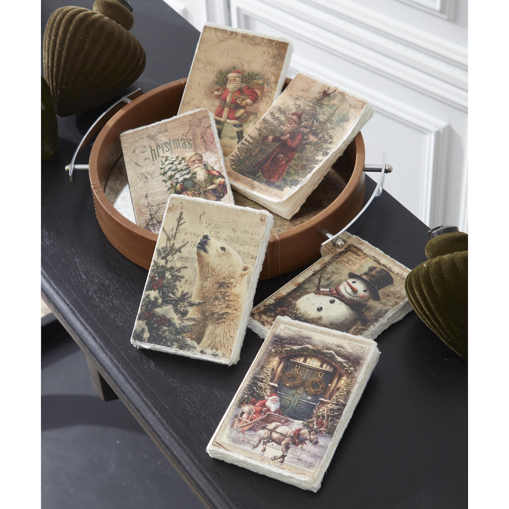 A lifestyle arrangement featuring assorted soft-cover Christmas journals with vintage illustrations and deckle edges displayed on a table and tray.