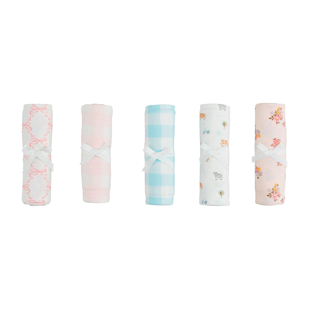 Set of five rolled soft-knit baby swaddle blankets in pink, blue, gingham, floral, and farm animal prints with white bows.