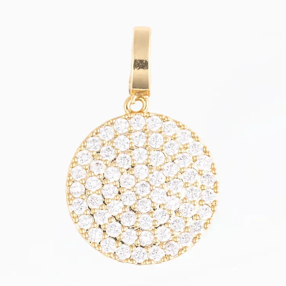Round gold pendant charm fully encrusted with pavé-set clear crystals on a plain white background.