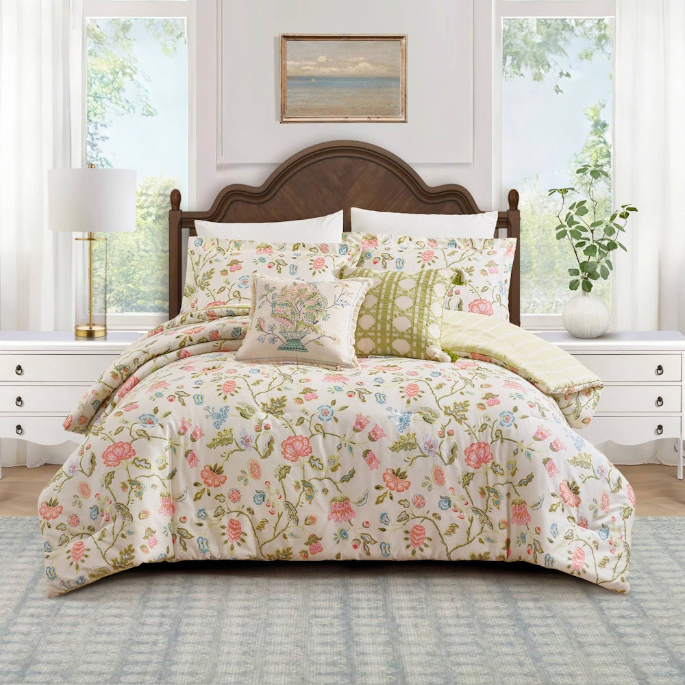 Floral comforter set with pink and blue flowers on a white bed in a bright bedroom with a wooden headboard.