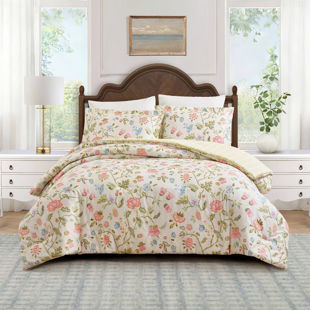 Floral garden comforter set with pink and blue flowers on a white bed in a bright, modern bedroom.