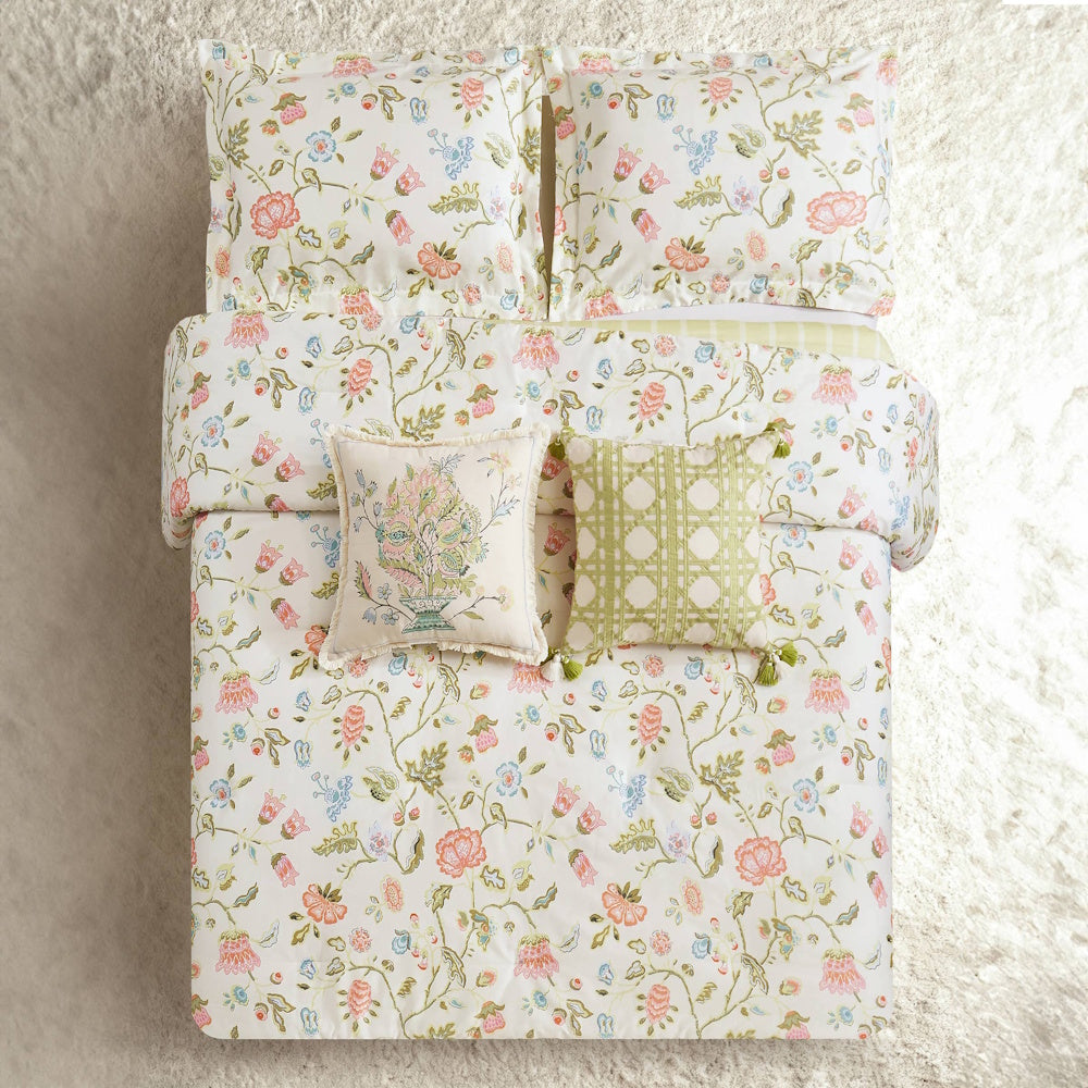Floral bedding set with pink and blue vines, matching shams, and decorative pillows on a white textured rug.