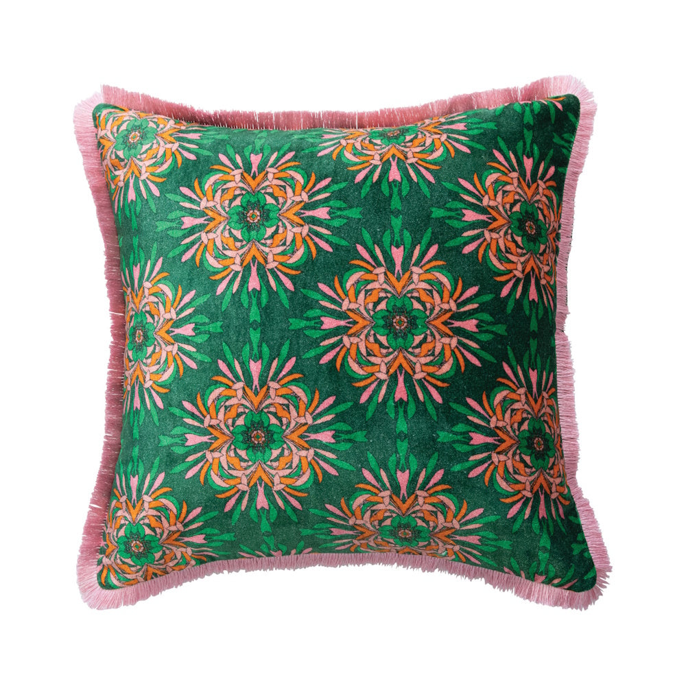 Green velvet pillow with a kaleidoscopic orange and pink floral pattern and pink eyelash fringe.