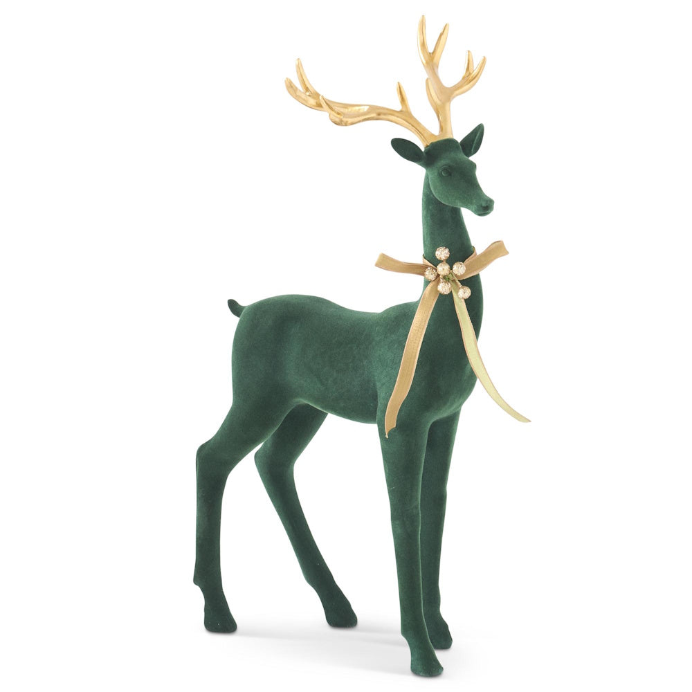 Front view of a standing dark green velvet deer figurine with gold antlers and a bow.