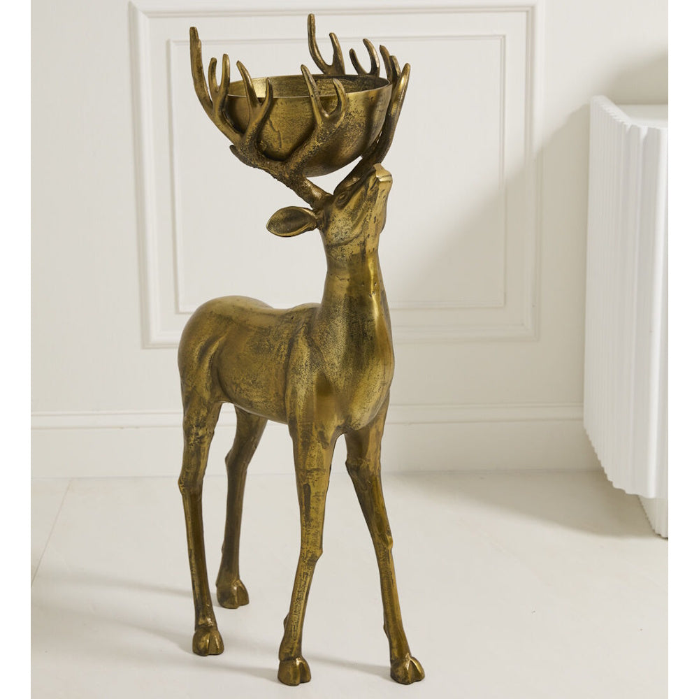 Bronze deer statue with a bowl in its antlers, standing indoors.
