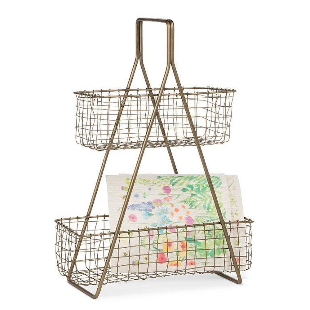 Two-tier antique brass wire caddy holding colorful floral napkins on a white background.