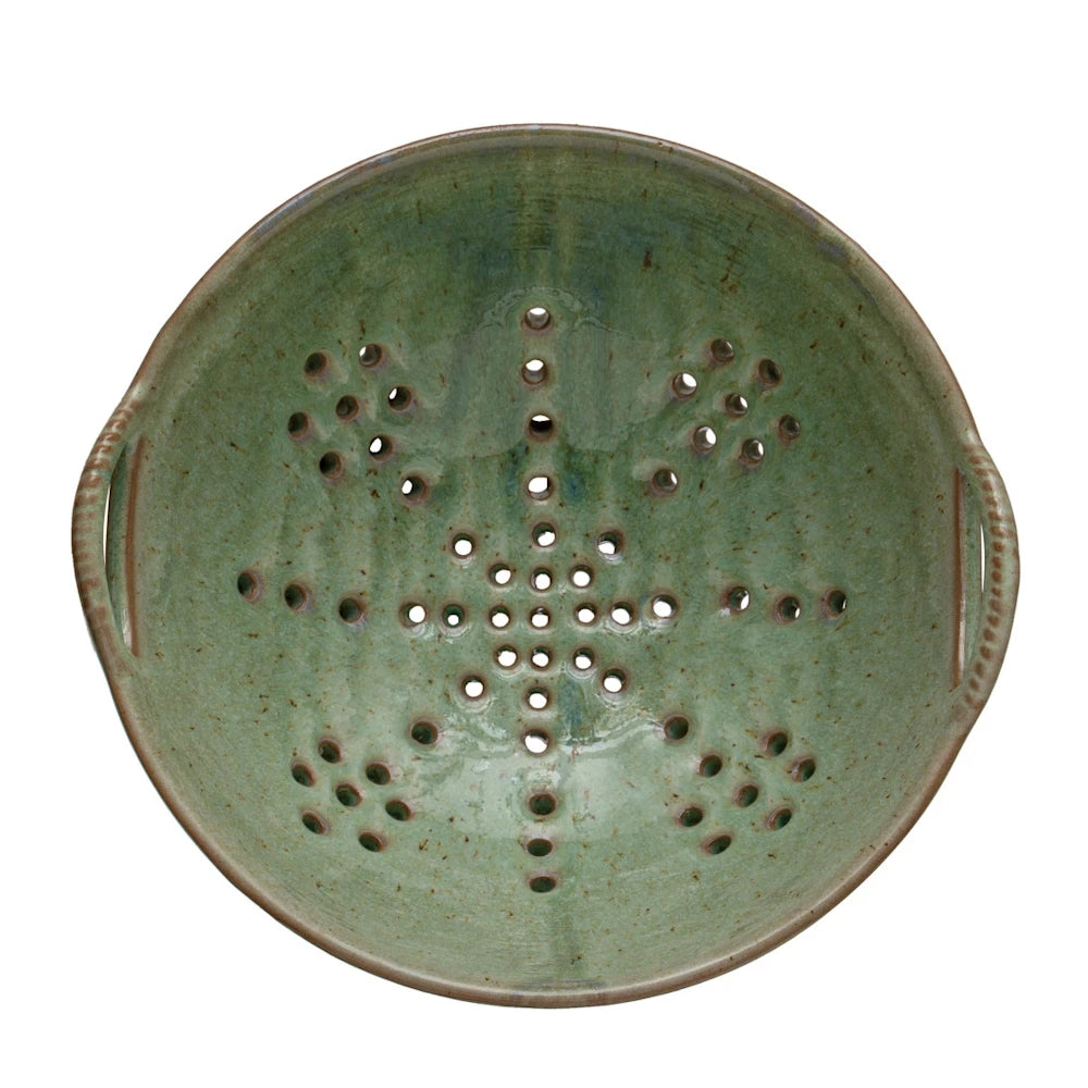Green speckled stoneware berry bowl colander with handles and drainage holes in a snowflake pattern.