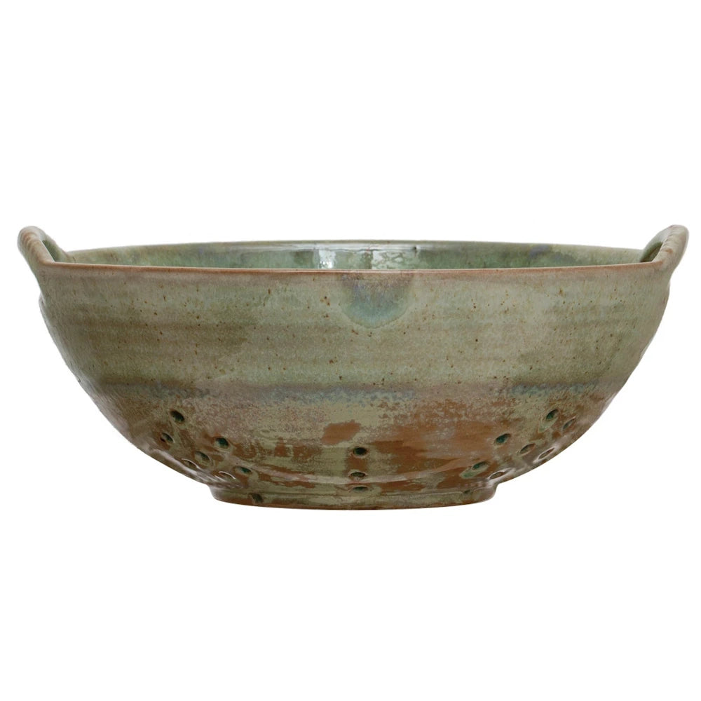 Green and brown stoneware berry bowl with handles and drainage holes, isolated on a white background.
