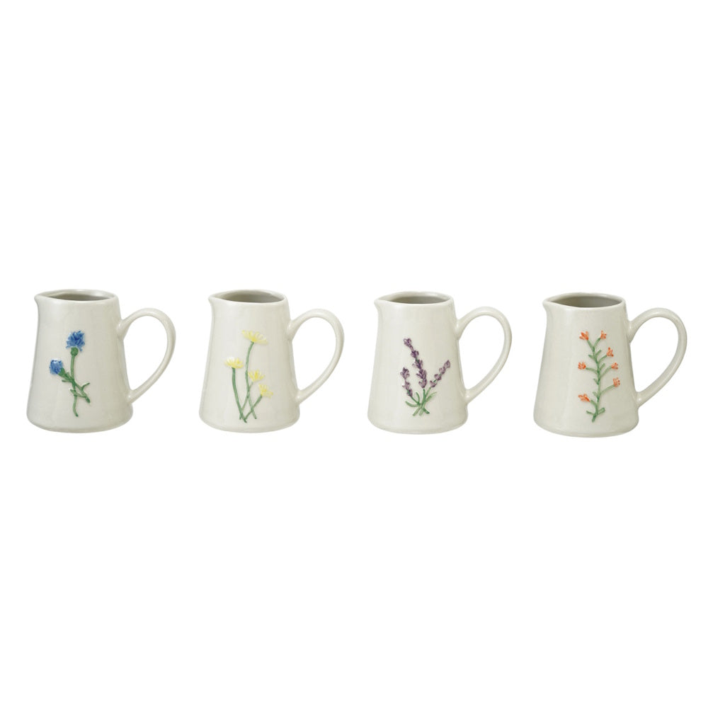 Lineup of four stoneware creamers featuring embossed botanical designs in blue, yellow, purple, and orange.