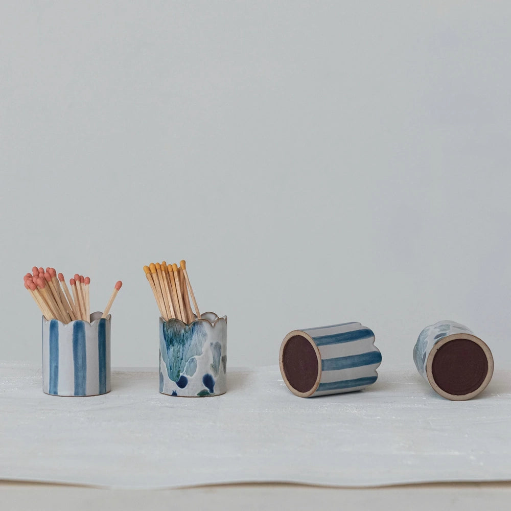 Scalloped white stoneware matchstick holders displayed upright with matches and resting on their sides to show the striker bottoms.