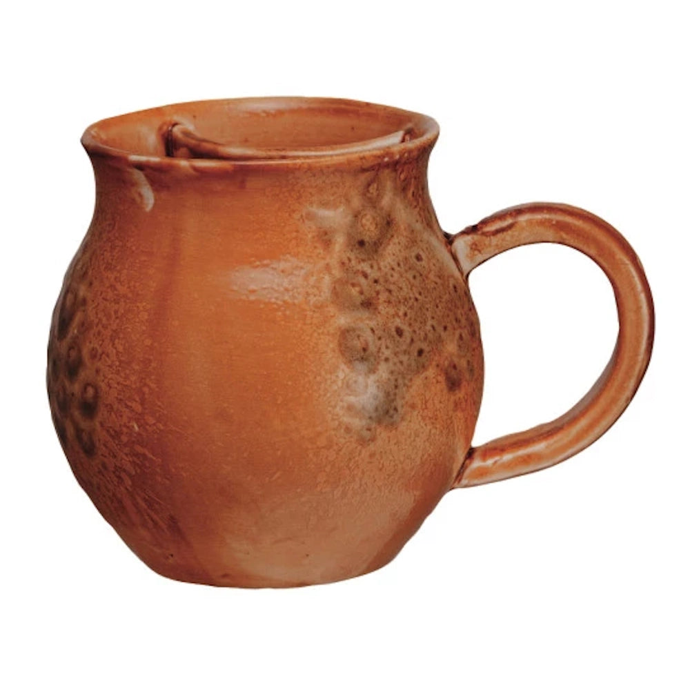 Rustic amber pottery shaving mug with handle and wide bowl for soap lathering.