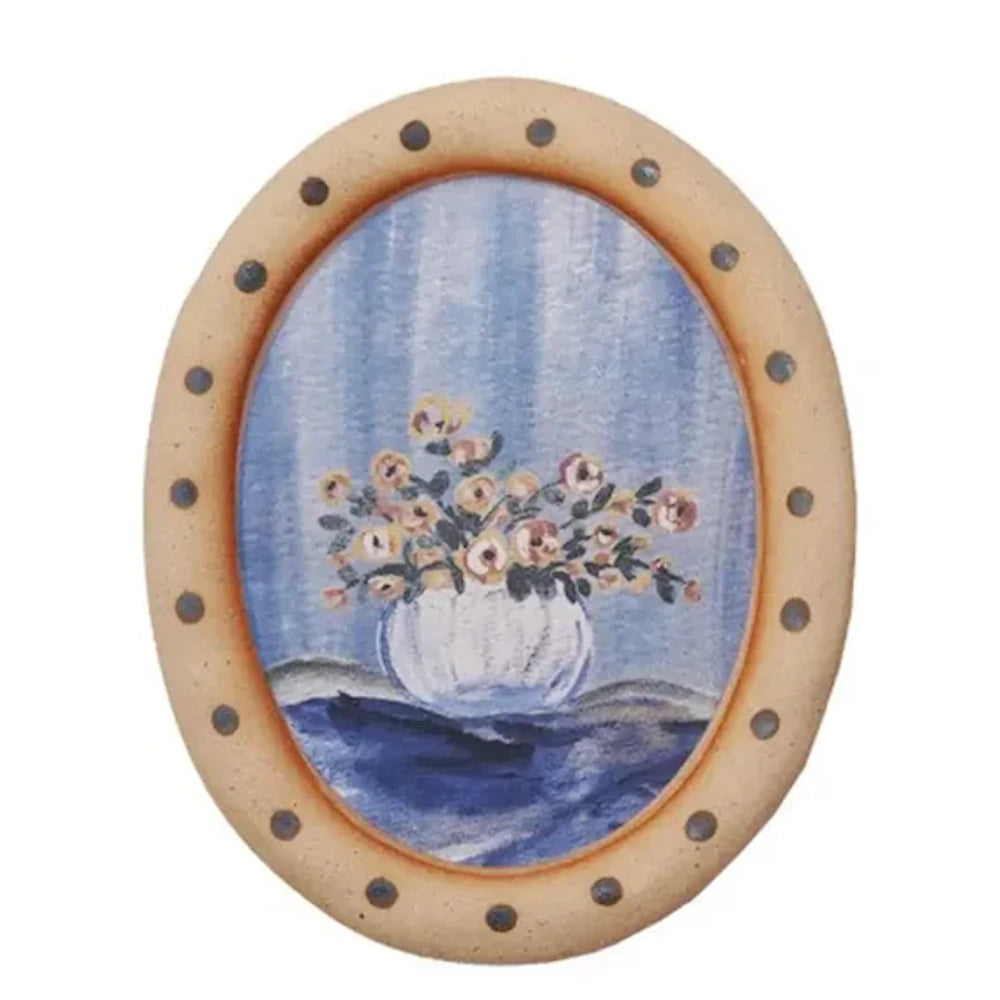 Hand-painted floral still life in an oval polka dot frame, featuring yellow and pink flowers in a white vase.