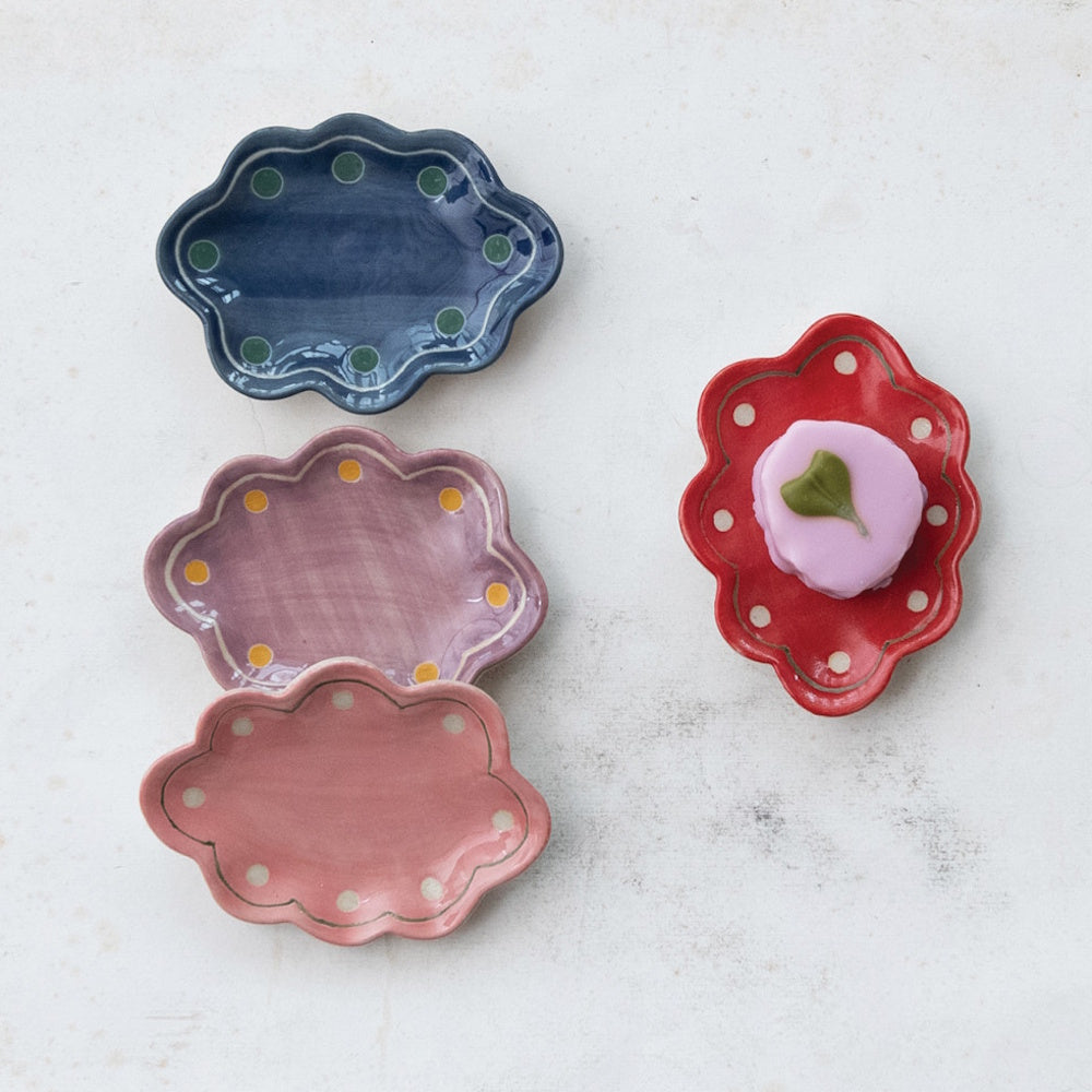 Colorful scalloped stoneware trinket dishes with polka dots, featuring a pink pastry on a red dish.