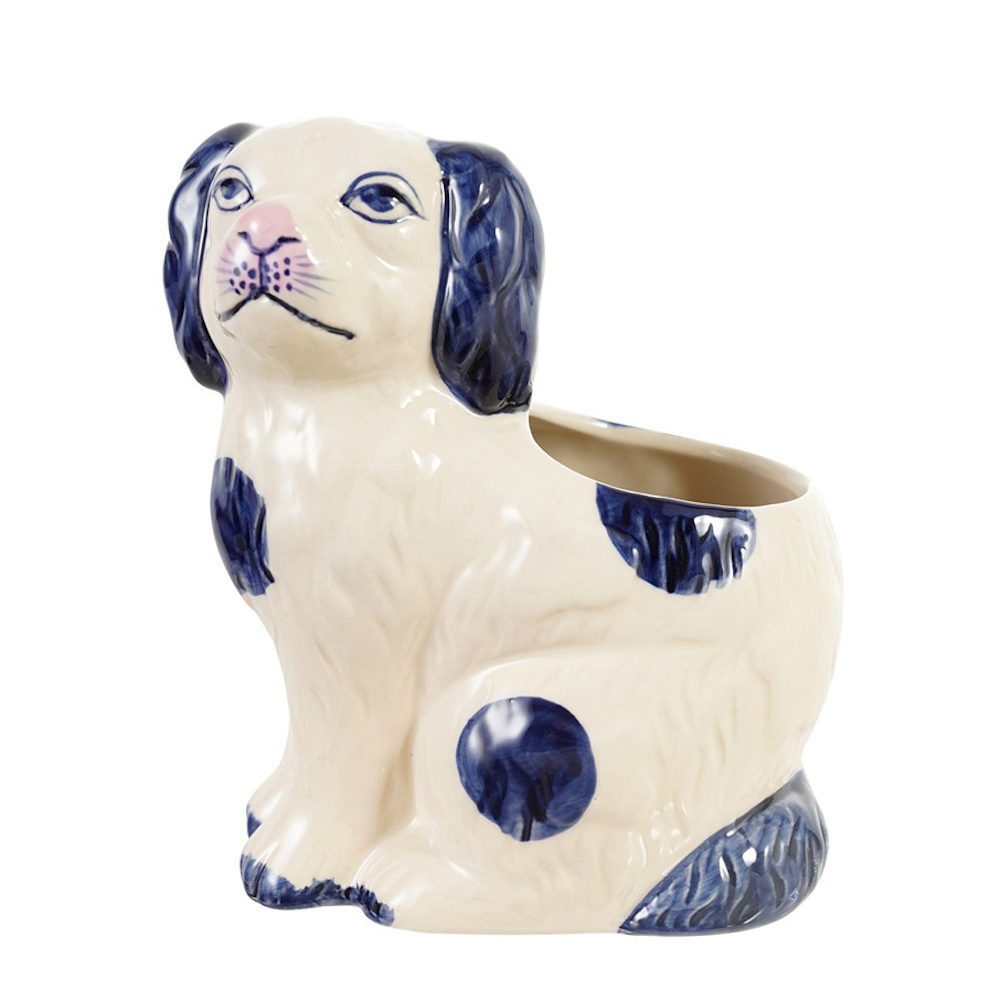 A white ceramic Staffordshire dog planter featuring navy blue ears and spots with an open back.