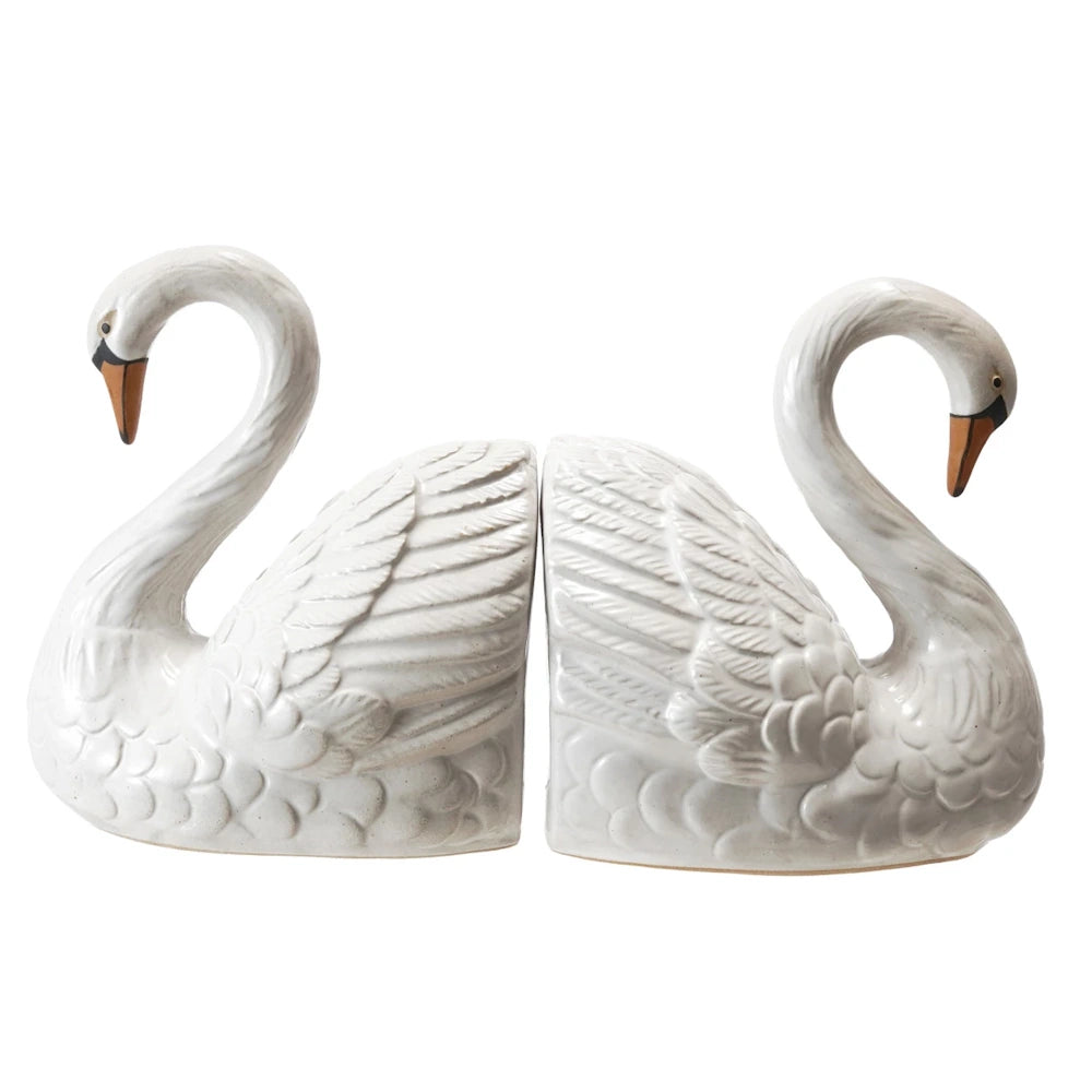 Pair of vintage-style white ceramic swan bookends with textured feathers and orange beaks on a white background.