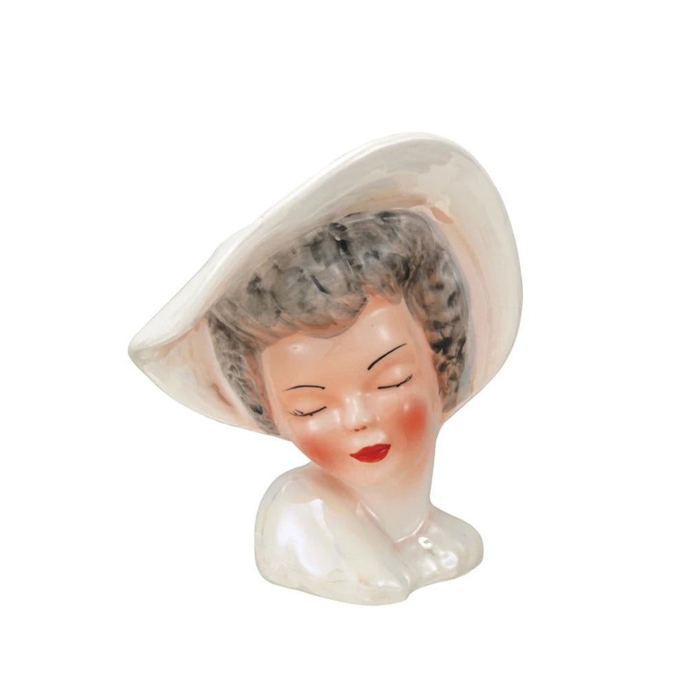 Side view of a vintage reproduction ceramic lady head vase featuring a white wide-brimmed hat.