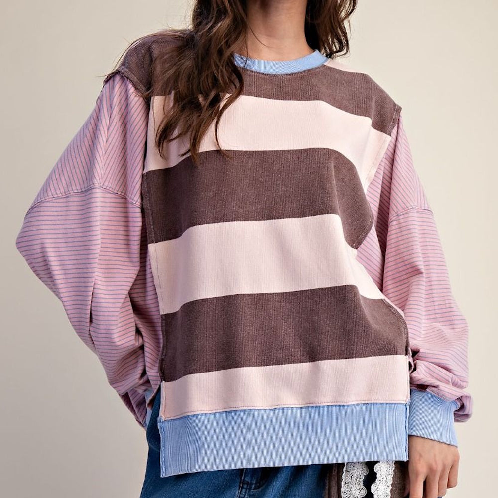 Woman wearing a brown and pink striped pullover sweater with fine-striped sleeves and blue trim.