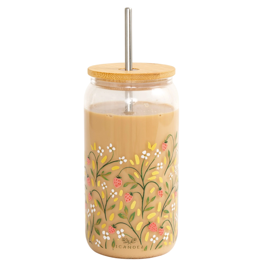 Glass tumbler with a floral strawberry pattern filled with iced coffee, featuring a bamboo lid and metal straw.