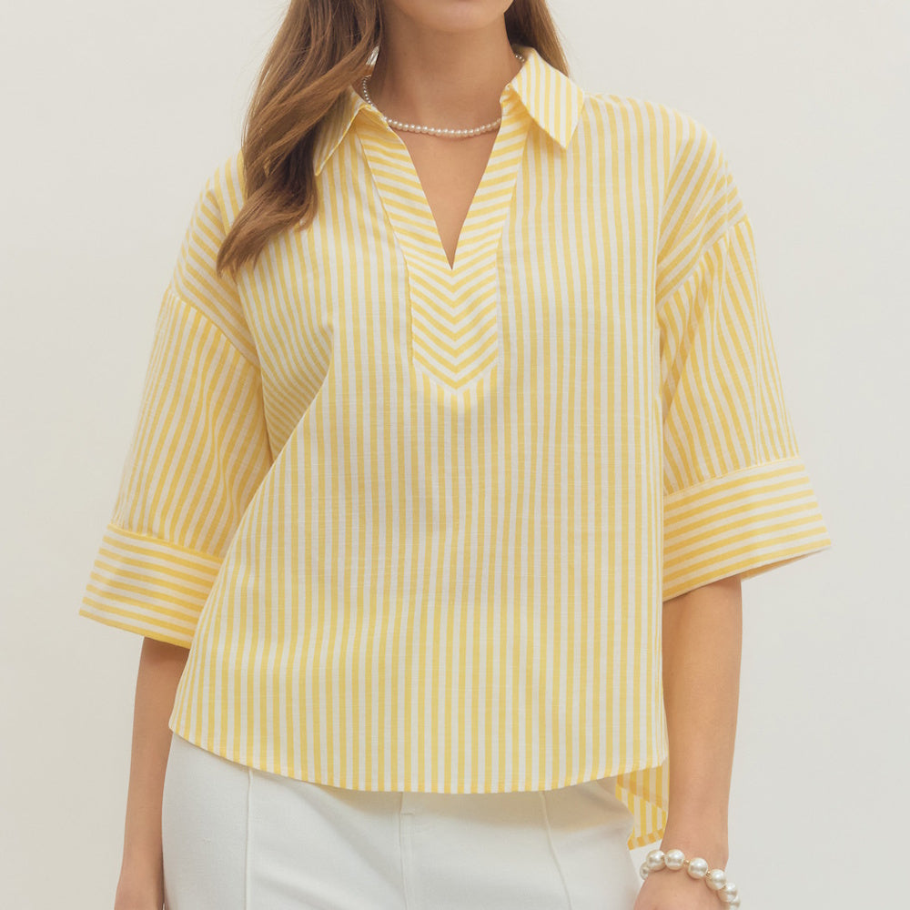 Yellow and white striped split V-neck top with three-quarter sleeves worn with white pants.