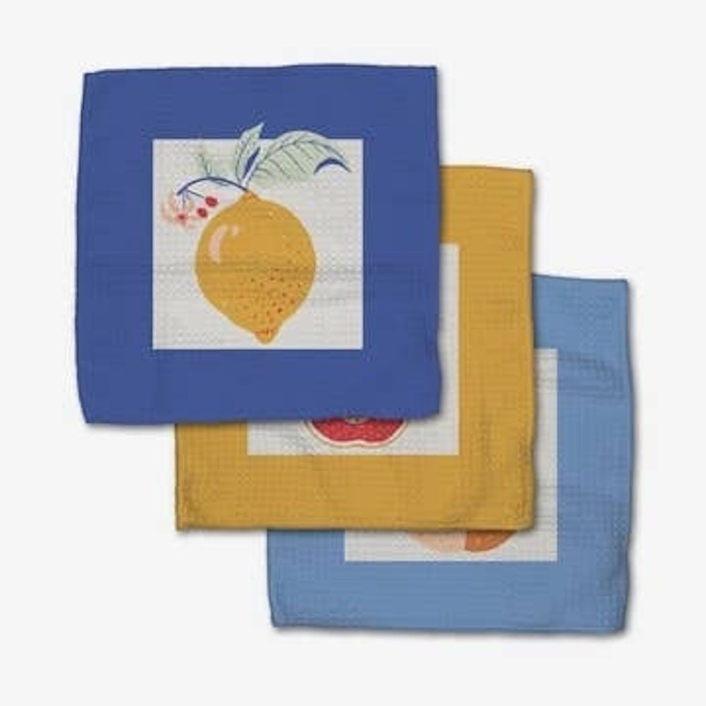 Three colorful, textured dishcloths with fruit illustrations, including a yellow lemon on a blue cloth.