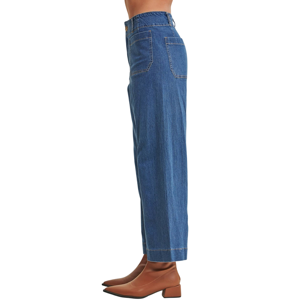 Side view of wide-leg blue denim jeans with patch pockets, paired with brown leather ankle boots.