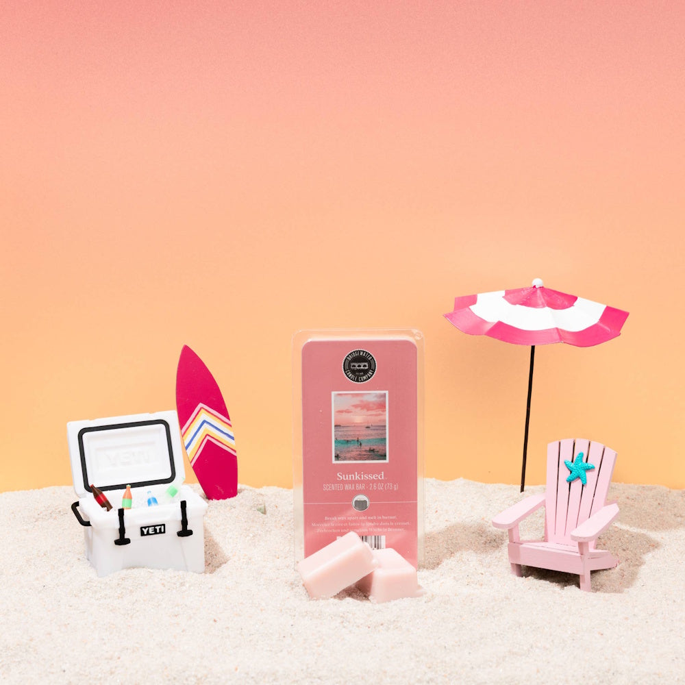 Bridgewater Sunkissed scented wax melts on sand with miniature beach chair, cooler, and surfboard summer decor.