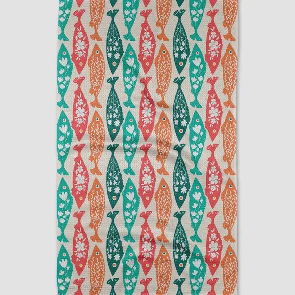 Tea towel with a patterned print of red, orange, green, and teal fish detailed with floral designs.