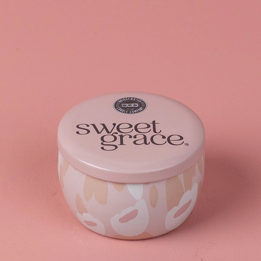 Pink floral patterned Sweet Grace candle tin with lid on a matching pink background.