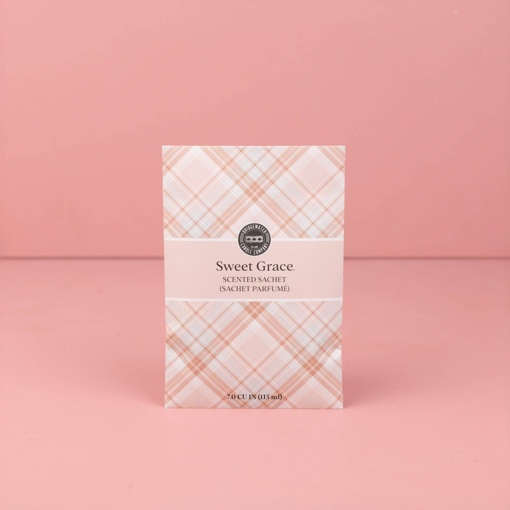 Sweet Grace pink plaid scented sachet packet standing upright on a solid pink surface.