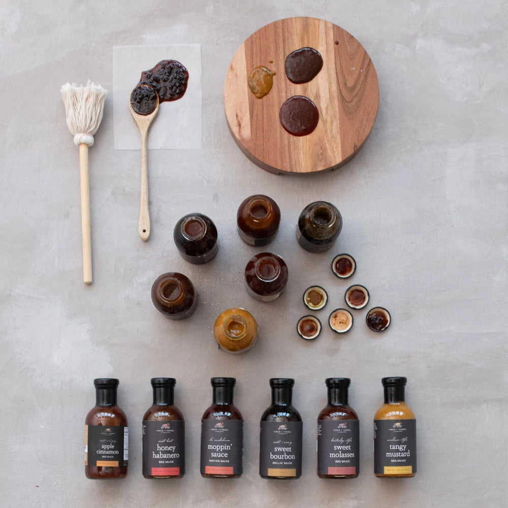 Assorted BBQ sauces in bottles and bowls, including Honey Habanero and Tangy Mustard, with a basting mop.