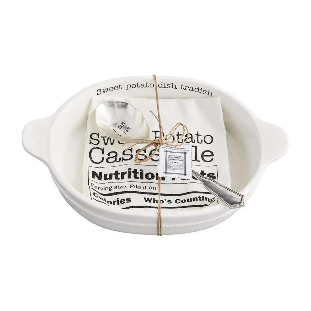 White ceramic baking dish set with a printed kitchen towel and stamped serving spoon tied in twine.