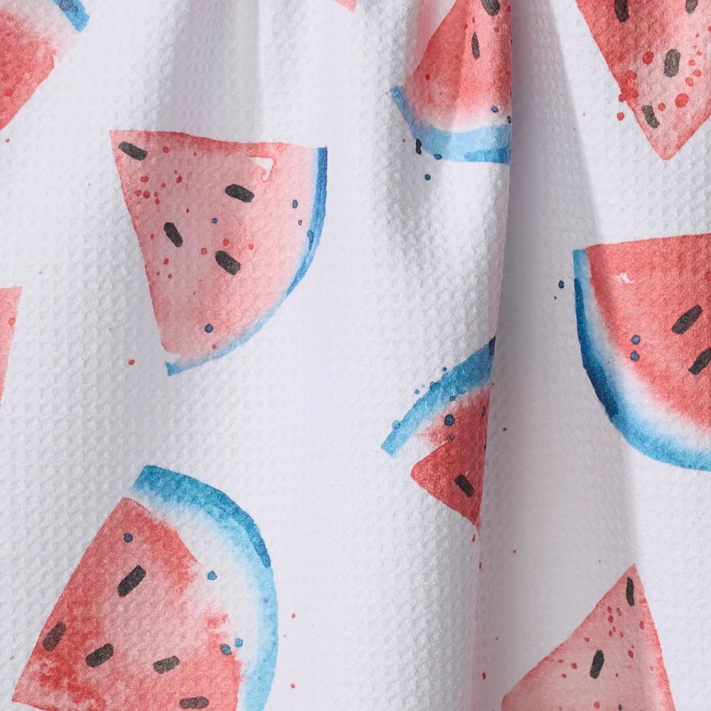 Close-up of white waffle-weave fabric with a watercolor pattern of pink and blue watermelon slices.
